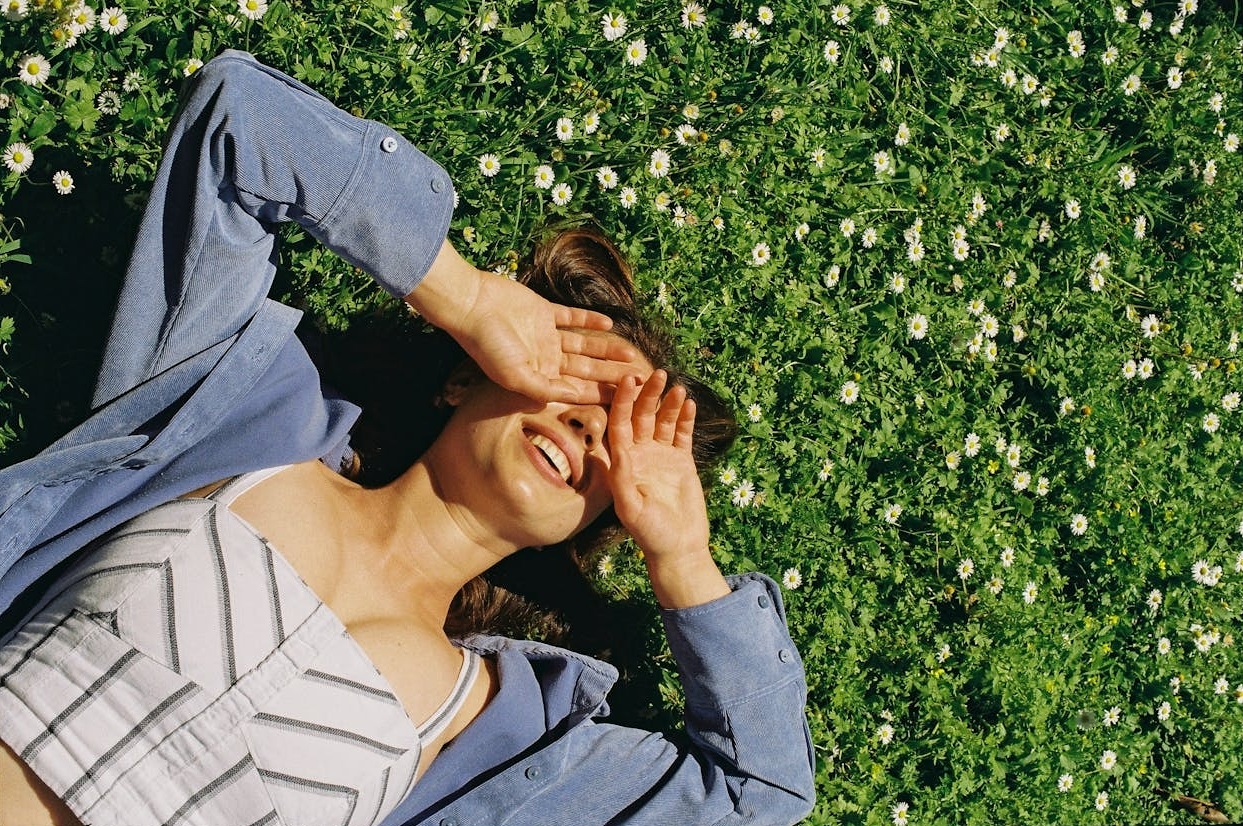 Eine Frau liegt in einer sommerlichen Blumenwiese